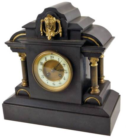 A Victorian black slate mantel clock, with neo-classical case, surmounted by a raised head above a 10cm Dia, Arabic dial flanked by columns, with an 8-day movement, 36cm H.