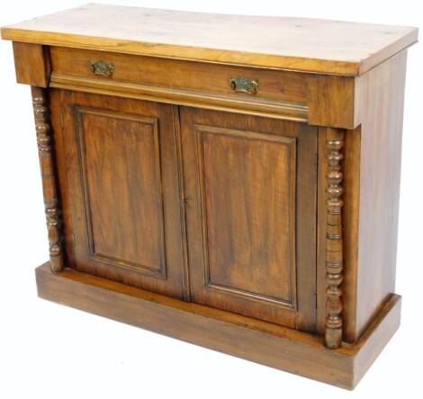 A 19thC walnut side cabinet, of rectangular form with a frieze drawer above a double panelled cupboard, flanked by circular columns on a block base, 86cm H, 103cm W, 40cm D.