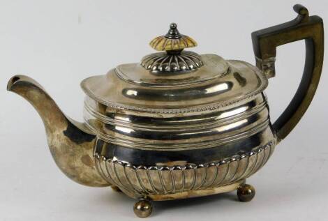 A George III silver teapot, of squat square form, with gadrooned rim, with ivory knop and ebonised handle, on bun feet, 16cm H, London 1811, 20oz.