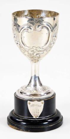 A Victorian silver prize cup, embossed with cartouche and flowerhead and scroll decoration, London 1862, on an ebonised socle with shield engraved 'Mrs Holt, 1938, 1939, 1940', 19cm H overall.