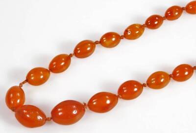 An orange agate longuard necklace, with graduated oblong beads, the largest 22mm, the smallest 14mm, on orange string strand, 55cm high overall. - 2