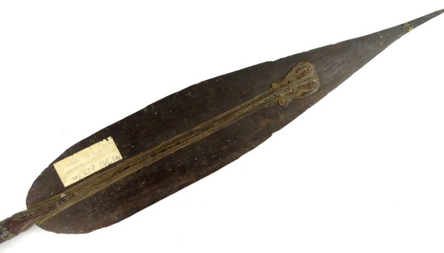 A Papua New Guinea tribal paddle, with carved blade, tapering handle and shaped finial, bearing label stating Aborigine boat paddles, brought to England 1910, 182cm L.