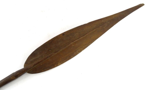 A Papua New Guinea tribal paddle, with leaf shaped blade, tapering handle with carved finial, bearing label stating Aborigine boat paddles, brought to England 1910, 153cm L.