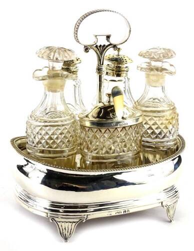 A George IV silver cruet, the boat shaped stand with gadrooned border and tapering feet, housing six cut glass bottles some with matching silver mounts, bottles AF, London 1825, 16.5cm W.