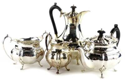 A George V silver four piece tea service, each piece with G shaped body, the teapot and hot water pot with ebonised knop and handle and scroll feet, Sheffield 1926, 57½g gross.