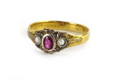 A Victorian style dress ring, set with oval cut garnet in white metal rub over setting, flanked by two seed pearls, on a later yellow metal band, unmarked, but bearing partial rubbed inscription, ring size N, 2.1g all in.