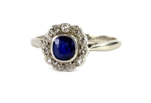 A sapphire and diamond floral cluster ring, with central small sapphire in rub over setting, surrounded by tiny diamonds, each in rub over setting, with pierced shoulders, on a white metal band, unmarked, possibly white gold, the inner band inscribed Pip