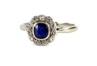 A sapphire and diamond floral cluster ring, with central small sapphire in rub over setting, surrounded by tiny diamonds, each in rub over setting, with pierced shoulders, on a white metal band, unmarked, possibly white gold, the inner band inscribed Pip