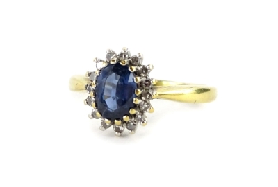 An 18ct gold sapphire and diamond dress ring, with oval cut pale blue stone, surrounded by tiny diamonds, each in claw platinum setting, ring size J, 3.8g all in.