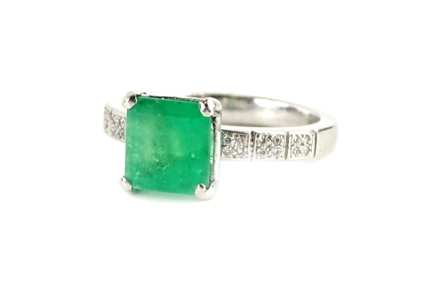 A platinum emerald and diamond ring, with central square cut emerald, in claw setting, approx 1.81cts, with tiny diamond set shoulders, comprising three square sections each with four pave set stones, ring size L, 6.6g all in.