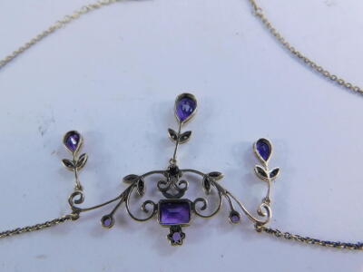 An Art Nouveau design pendant, florally in scroll set with small diamonds and purple amethyst coloured stones, with a pear shaped large stone to the base attached to a standard link chain. - 2