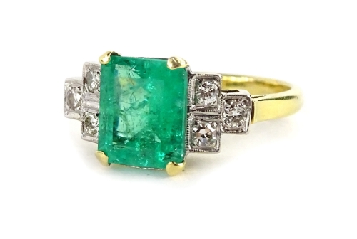 An emerald and diamond ring, with central rectangular cut emerald, in yellow gold claw setting, approx 2.51cts, with round brilliant cut diamond shoulders, three to each side, ring size M, 5.3g all in.