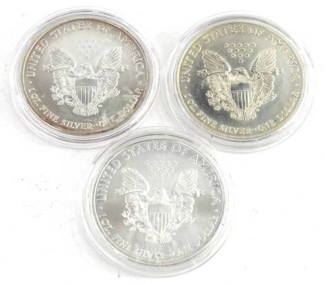 Three United States silver dollars, comprising 2004, 2009 and 1996.