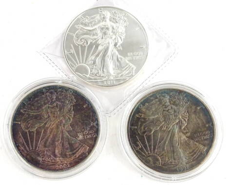 Three United States silver dollars, comprising 2011, 1997 and 2002.
