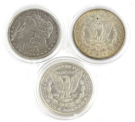 Three United States silver dollars, dated 1884, 1889 and 1886.