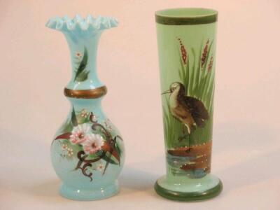 An opaque green glass vase painted with a stork and bull rushes