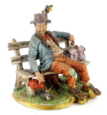 A Capodimonte porcelain figure of a tramp on a bench, sculpted by Volta, with certificate etc., 26cm W.