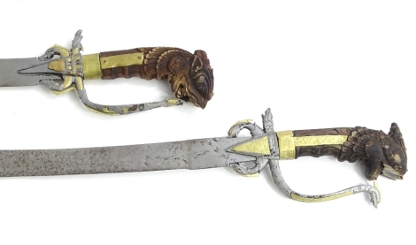 Two similar late 18th/early 19thC Ceylonese Kasane swords, each with a wooden handle carved in the form of a dragon, curved blade etc., (AF), 64cm L.