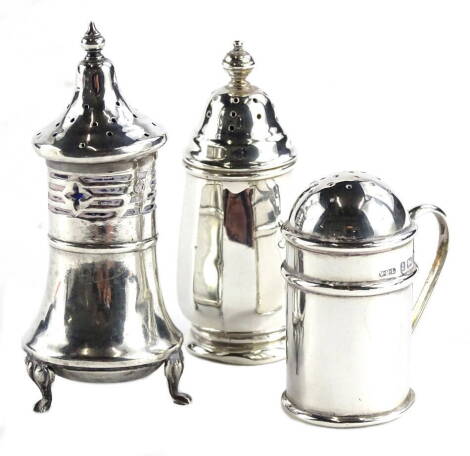 Three various silver pepper pots, one modelled in the form of a tankard, one with a blue glass liner.