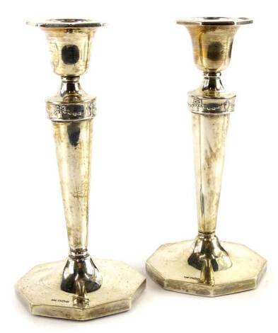 A pair of George VI silver candlesticks, each with an octagonal shaped top, cylindrical tapering column, decorated with swags etc., and an octagonal base, loaded, Sheffield 1937, 17cm H.