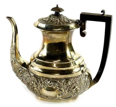 An Edwardian silver coffee pot, with embossed decoration of scrolls, surrounding a vacant cartouche with ebonised knop and handle, Birmingham 1909, 22¾oz, 22cm H.