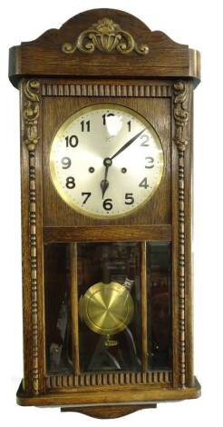 A Junghans oak wall clock, with silvered dial, the case decorated with bead and reel scroll motifs etc., 79cm L.