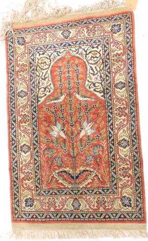 A Turkish silk small prayer rug, with a design of birds in a tree, on a red ground with one wide and two narrow borders, 41cm x 61cm.