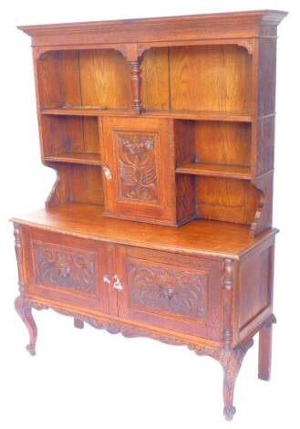 An early 20thC carved oak dresser, the raised plate rack with a central carved panel door, decorated with dragons, flanked by recesses etc., the bow fronted base with two carved panel doors on cabriole legs, 137cm W.