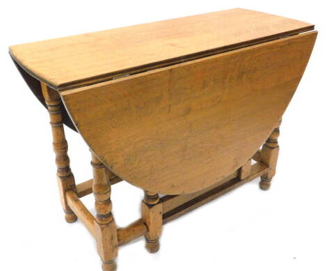 An oak oval drop leaf table, on turned supports with bun feet, 106cm W.