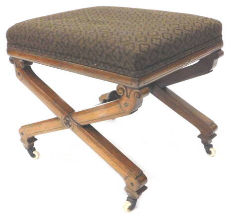 A Victorian walnut stool, with a padded seat and x shaped supports, on ceramic castors.