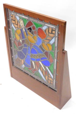 A stained glass panel, decorated in the form of a lady wearing a flowing dress etc., mounted in a hardwood frame, 62cm W overall.