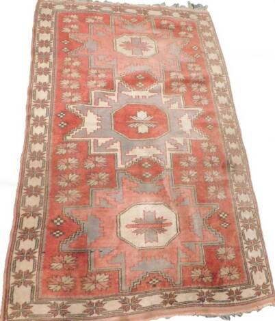 A Turkish rug, with a design of three medallions on a red ground, 162cm x 103cm.