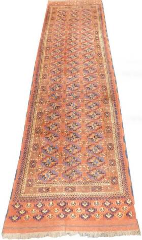 A Persian Turkoman style runner, with a design of medallions, on a rust colour ground.