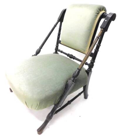 A Victorian ebonised aesthetic nursing chair in the manner of Godwin, with a padded back and seat on part turned end supports.