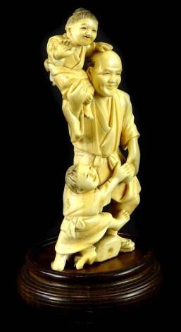 A late 19thC Japanese ivory Okimono, carved in the form of gentleman carrying two young children, (AF), signed to underside, 15cm H, and a hardwood stand.