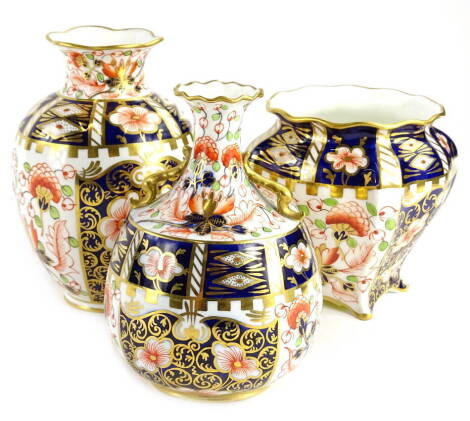 Three Royal Crown Derby porcelain vases, to include a two handled vase decorated in the Imari pattern, printed mark in red to underside, another similar, and a jardiniere type vase on a square foot, the largest 15cm H.