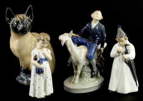 A collection of Royal Copenhagen and other figures, a Siamese cat, a figure riding a goat, a child with a doll and a young boy with night dress and parasol.