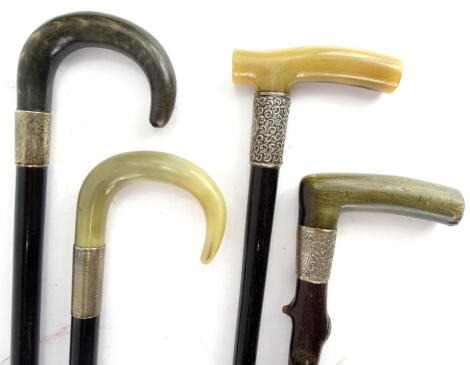 A collection of walking sticks, each with a silver collar and a horn handle, to include three ebonised examples.