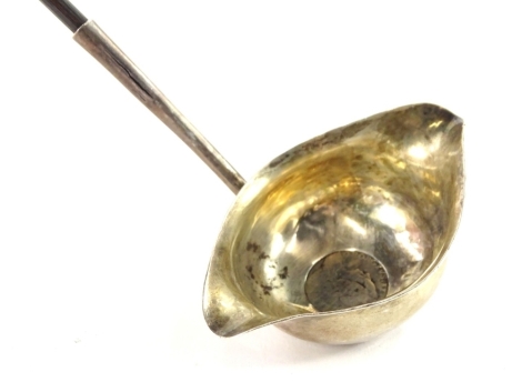 An early 19thC silver double lipped ladle, inset with a silver coin, date indistinct, and hallmark also indistinct, with twisted whale bone handle.