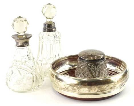 A silver coaster, with turned mahogany base, two cut glass scent bottles with silver collars, and dressing table jar. (4)