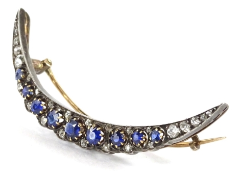 A sapphire and diamond crescent brooch, set with round brilliant cut stones, in claw setting, comprising nine graduated sapphires, and twenty four tiny diamonds, in silver coloured setting, with yellow metal pin back, unmarked, 5.5cm wide, 6.4g all in.