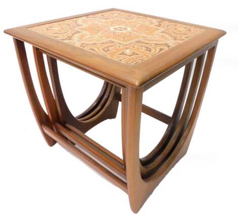 A nest of three G-plan teak tables, the largest inset with tiles, on end supports, 50cm wide.