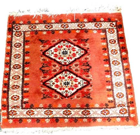 A small Turkish mat, with design of two medallions, on a rust coloured ground, with one wide border, 63cm x 57cm.