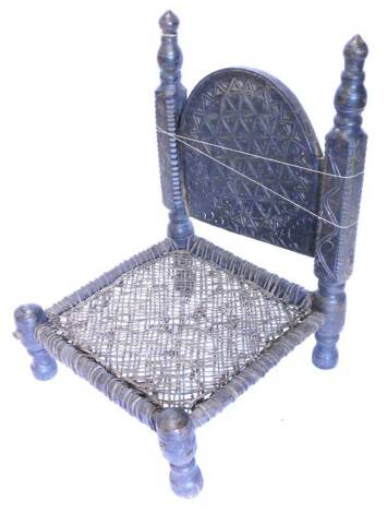 An Indian low chair, the arched back with geometric carving, on part turned supports, with rattan type seat and turned legs.