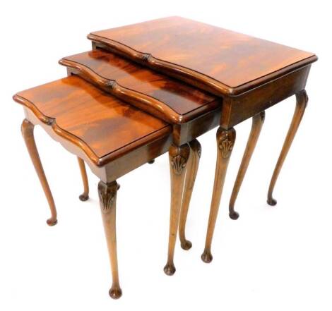 A nest of three mahogany occasional tables, each with a moulded shaped edge, on cabriole legs with pad feet, the largest 57cm wide.