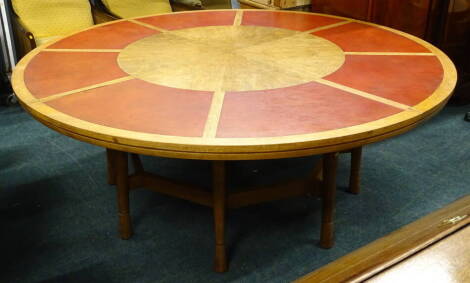 An unusual mahogany circular boardroom or dining table, the top inset with red leatherette segments, on turned legs with stretchers, 200cm dia.