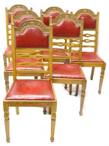 A set of six early 20thC oak dining chairs, each with a carved back, a red leatherette padded back and drop in seat, on square tapering legs, with collars.