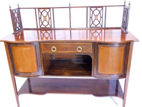 An Edwardian mahogany sideboard, with a raised back applied with turned brass finials, pierced supports centred by oval patera, the serpentine fronted base with a frieze drawer above a recess, flanked by two bow fronted panelled doors, above a shaped unde