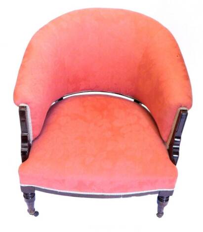 An Edwardian mahogany tub shaped chair, upholstered in peach floral damask fabric, on turned tapering legs.