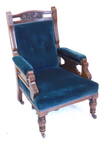 A late Victorian walnut armchair, with a button padded back, arm rests and seat, on shaped supports with part turned tapering legs and ceramic castors.